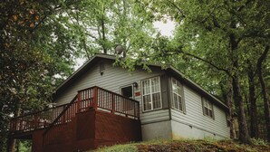 A two-story house with a wooden deck and a satellite dish on the roof, surrounded by trees. - MTN View Cottage Getaway Stunning Fall Colors Private Bathroom per bedroom (Sevierville)