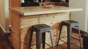 A kitchen with wooden cabinets, a wooden island with stools, a refrigerator, and a microwave. - MTN View Cottage Getaway Stunning Fall Colors Private Bathroom per bedroom (Sevierville)