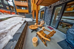 A covered outdoor seating area with wooden furniture and a stone wall.