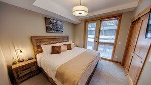 Ein Schlafzimmer mit Holz-Kopfteil, einem großen Bett mit weißer Bettwäsche, einer Nachttischlampe und einem Bild an der Wand.