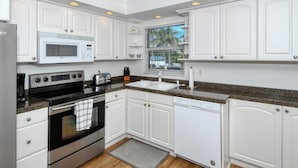 A modern kitchen with white cabinetry, stainless steel appliances, and granite countertops. - Condo#201 Beautiful condo on Siesta Key steps to the beach (Sarasota)