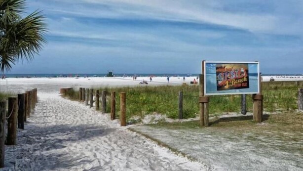 A beach pathway leading to a beach with a signboard. - Condo#201 Beautiful condo on Siesta Key steps to the beach (Sarasota)