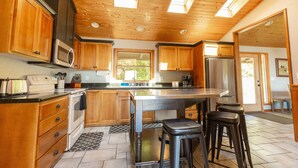 Une cuisine moderne avec des meubles en bois, un réfrigérateur en acier inoxydable et un grand îlot central doté de tabourets.