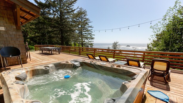 Un bain à remous sur une terrasse en bois, avec vue sur l’océan.