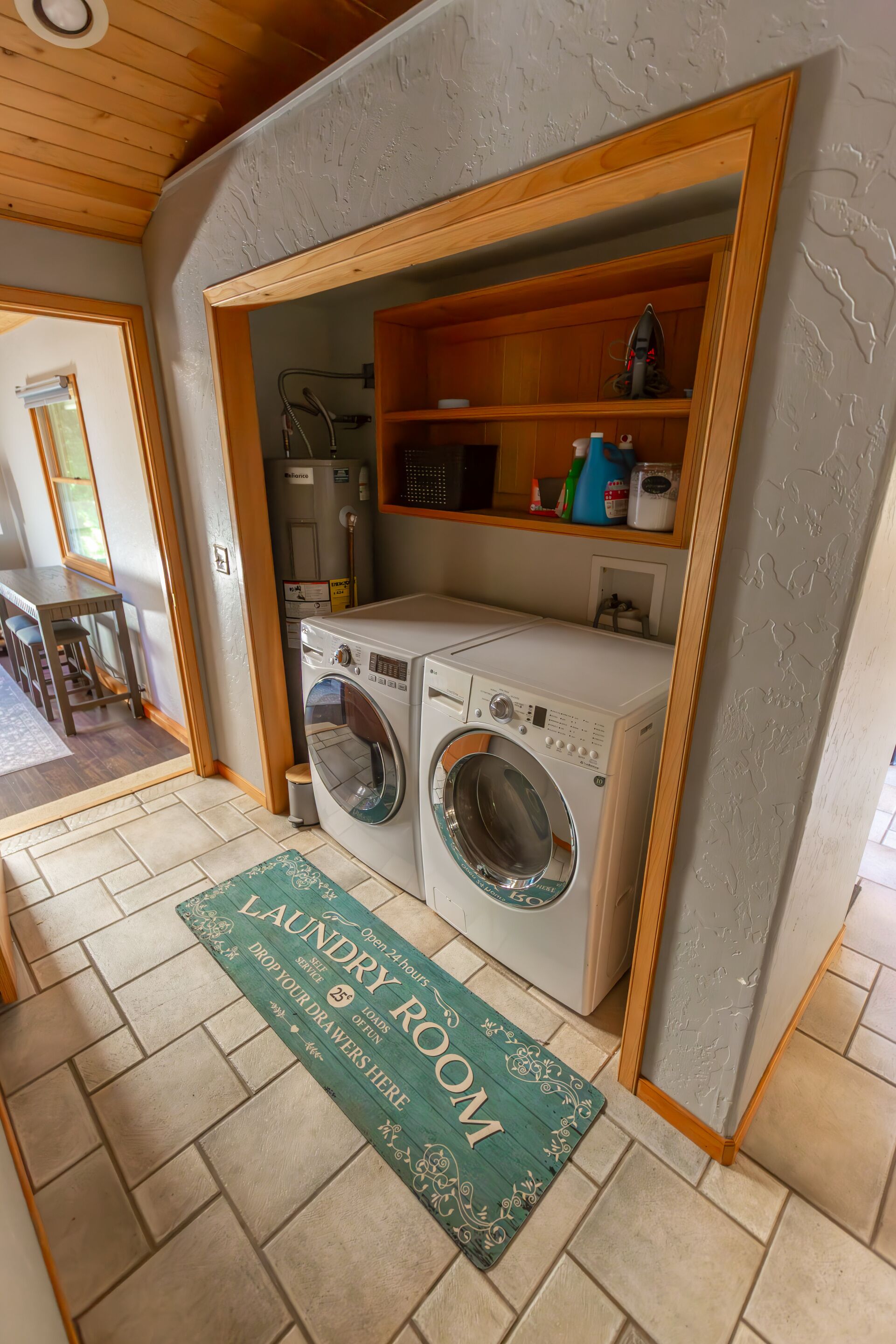 A laundry room with two washing machines, a drying rack, and a shelf with cleaning supplies.