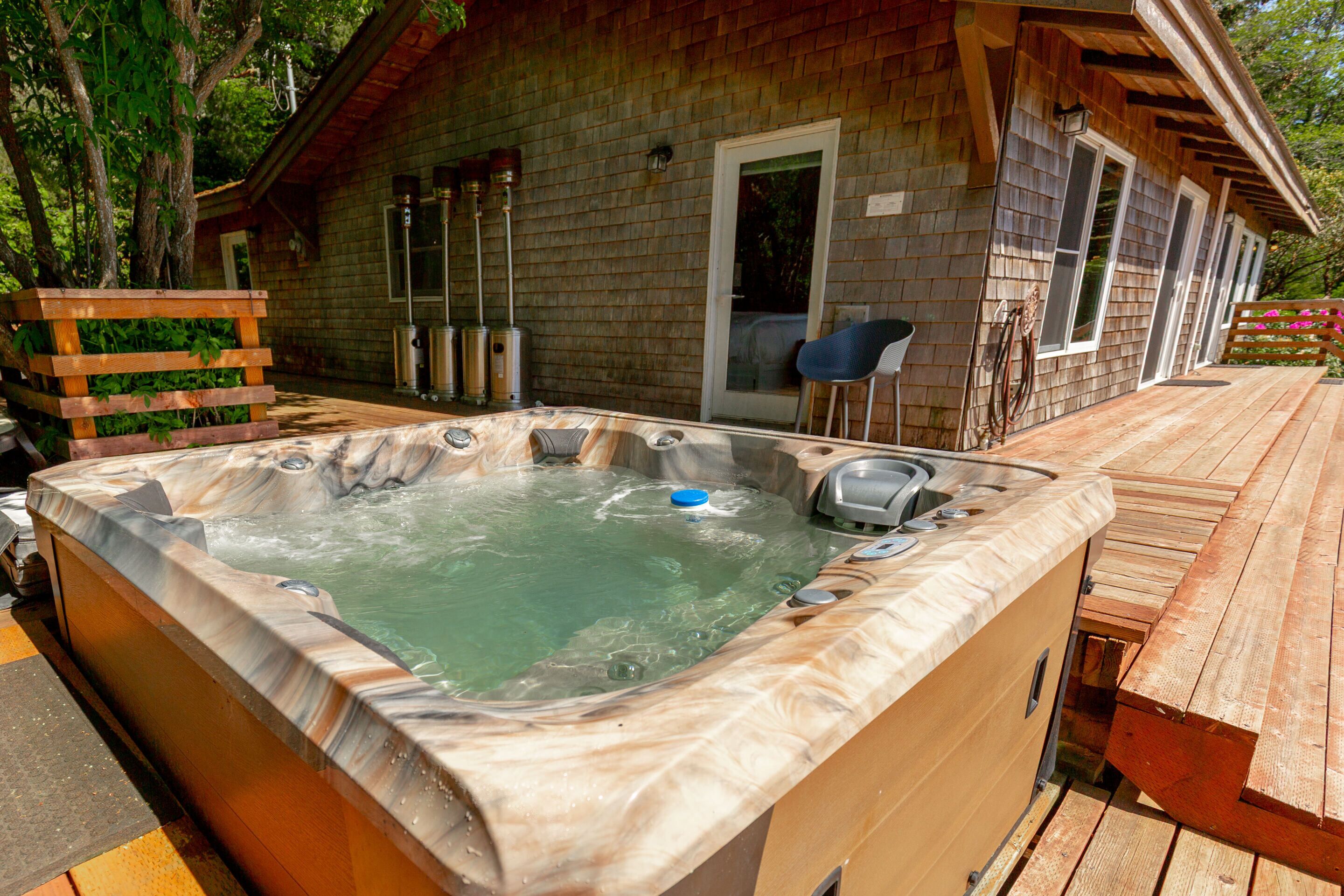 A hot tub with a wooden deck and a wooden cabin in the background.