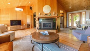 Un salon spacieux doté d’une cheminée, de parquets en bois et d’un téléviseur.