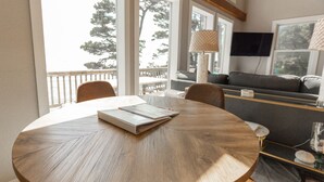 A round wooden table with a notebook and pen, a sofa with cushions, a lamp, and a TV mounted on the wall. - Honeymoon Cove at Crook Point (Brookings)