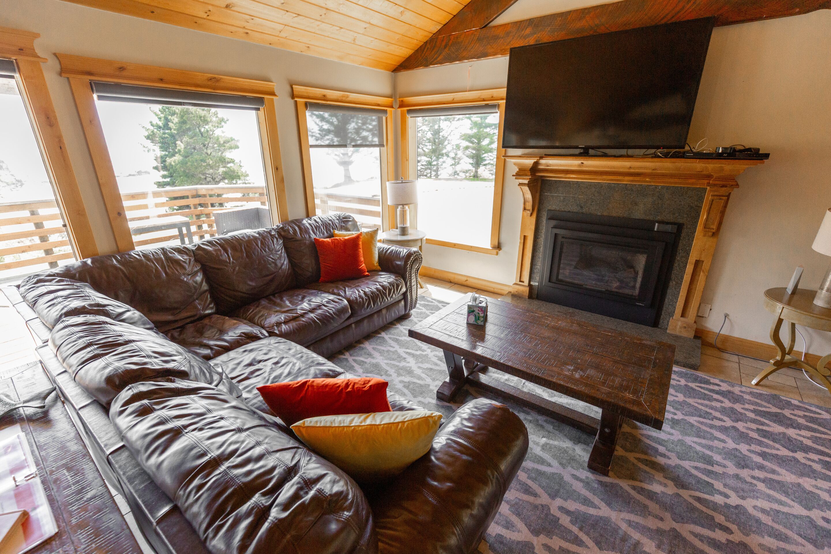 A cozy living room with a leather sofa, a wooden coffee table, and a fireplace.