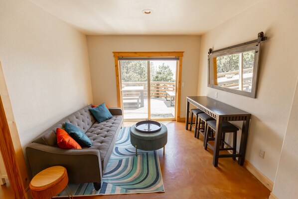 Una sala de estar acogedora con un sofá modular, una mesita redonda y una zona de comedor con taburetes de bar.