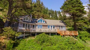 Eine Holzhütte mit einer Terrasse, umgeben von dichtem Wald.