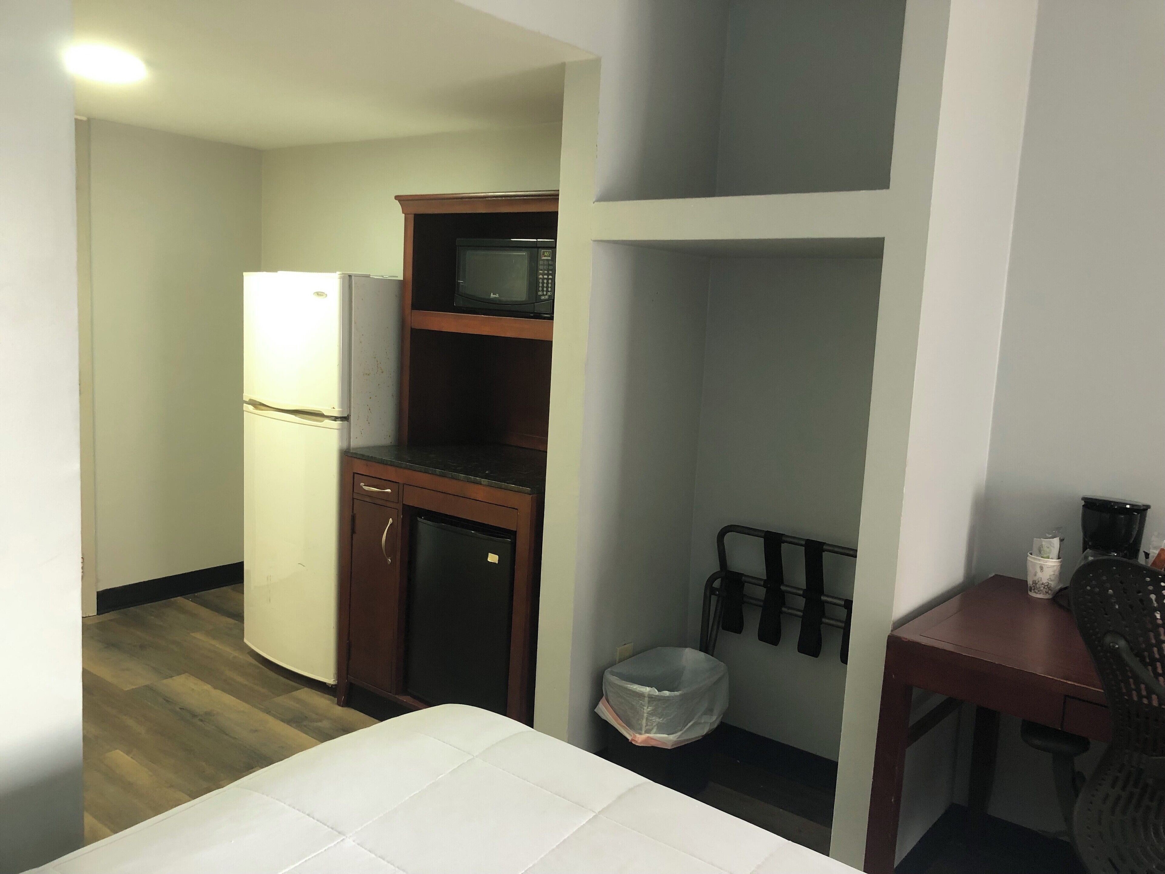 Una habitación de hotel compacta con kitchenette, una pequeña mesa de comedor y una silla.
