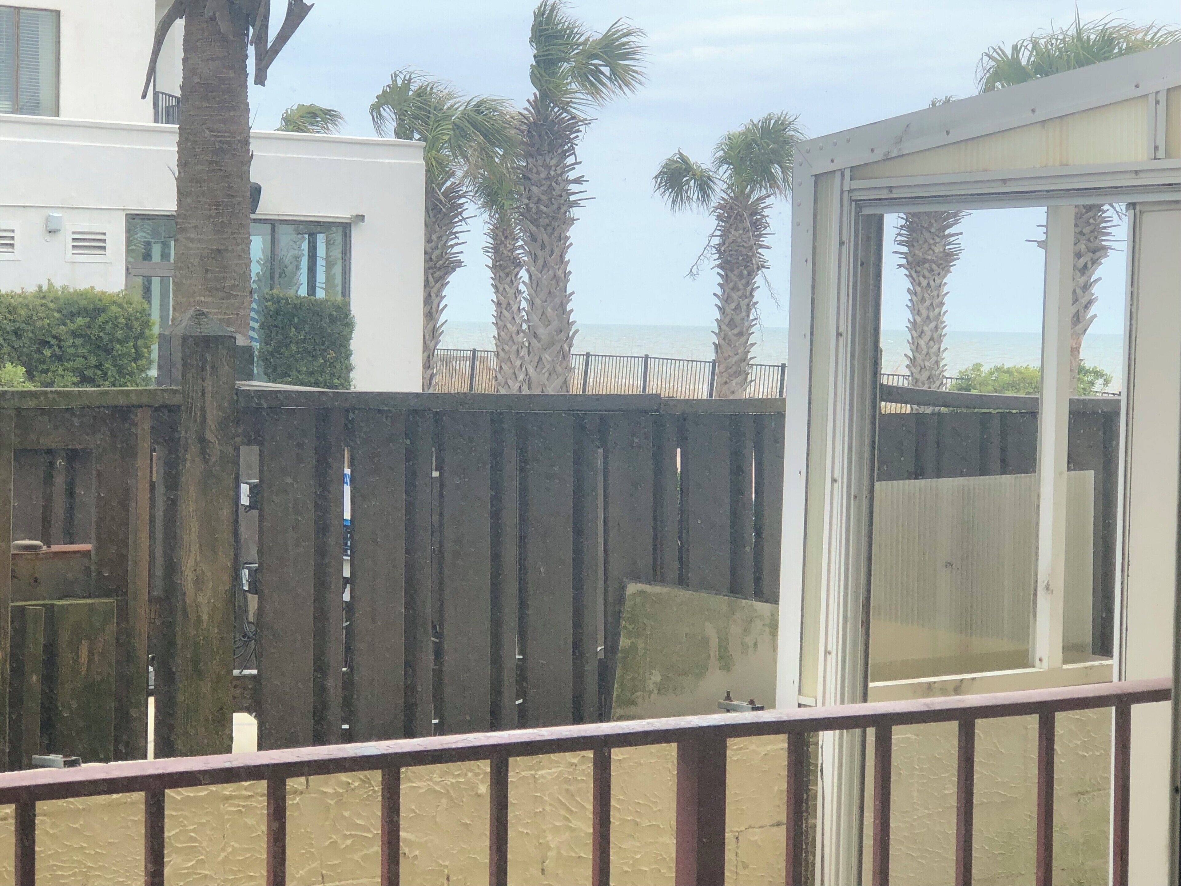 A balcony with a view of palm trees and a building in the background.