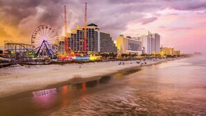 A beachfront hotel with a large Ferris wheel, a crane, and a beach in the foreground.