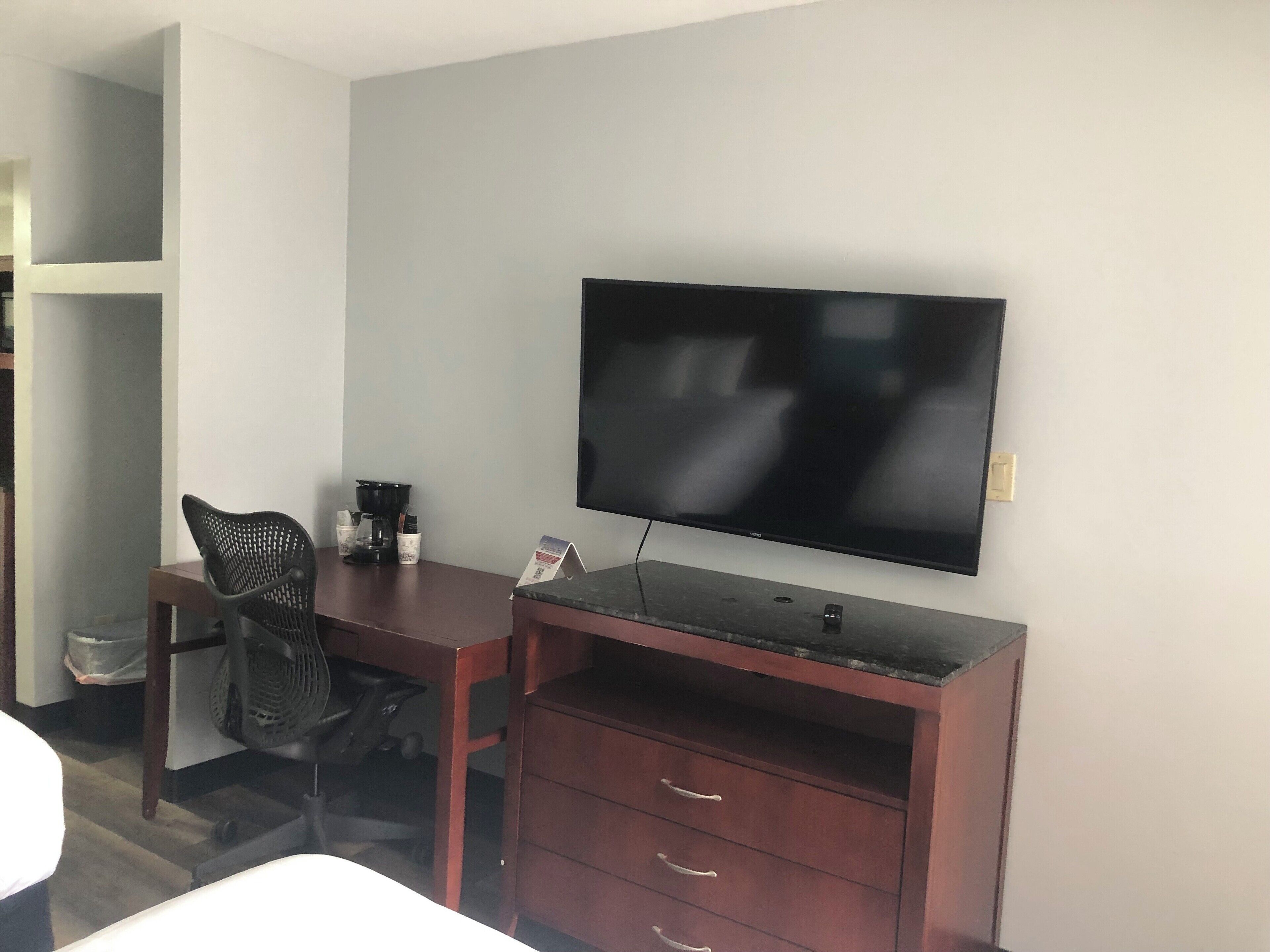 Une chambre d’hôtel équipée d’un bureau, d’une chaise, d’une télévision et d’un petit placard.