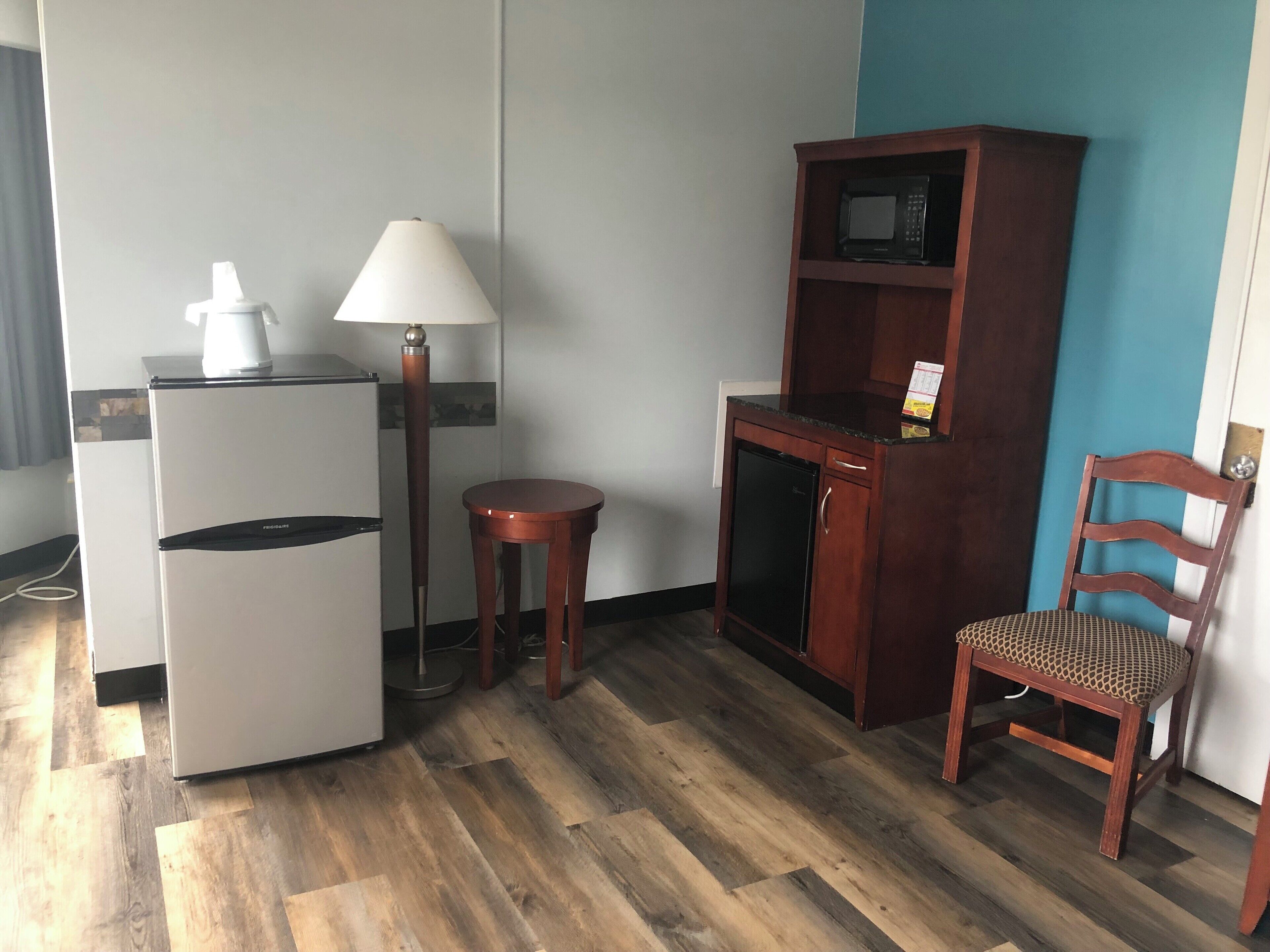 Una kitchenette compacta con refrigerador, microondas y un mueble pequeño.
