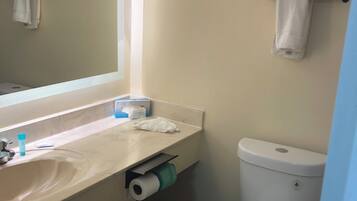 A bathroom with a sink, mirror, toilet, and towel rack.