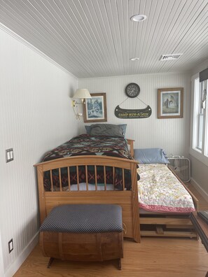 A bedroom with a wooden bed, a bench, a wall clock, and two framed pictures. - Lakefront house (Naples)
