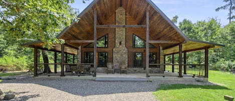 A lodge with a stone fireplace, wooden beams, and a covered patio area.