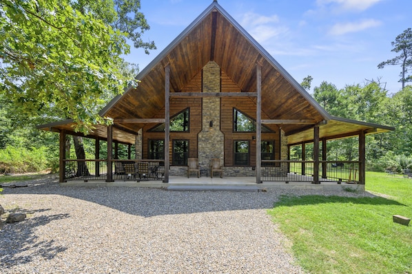A lodge with a stone fireplace, wooden beams, and a covered patio area.
