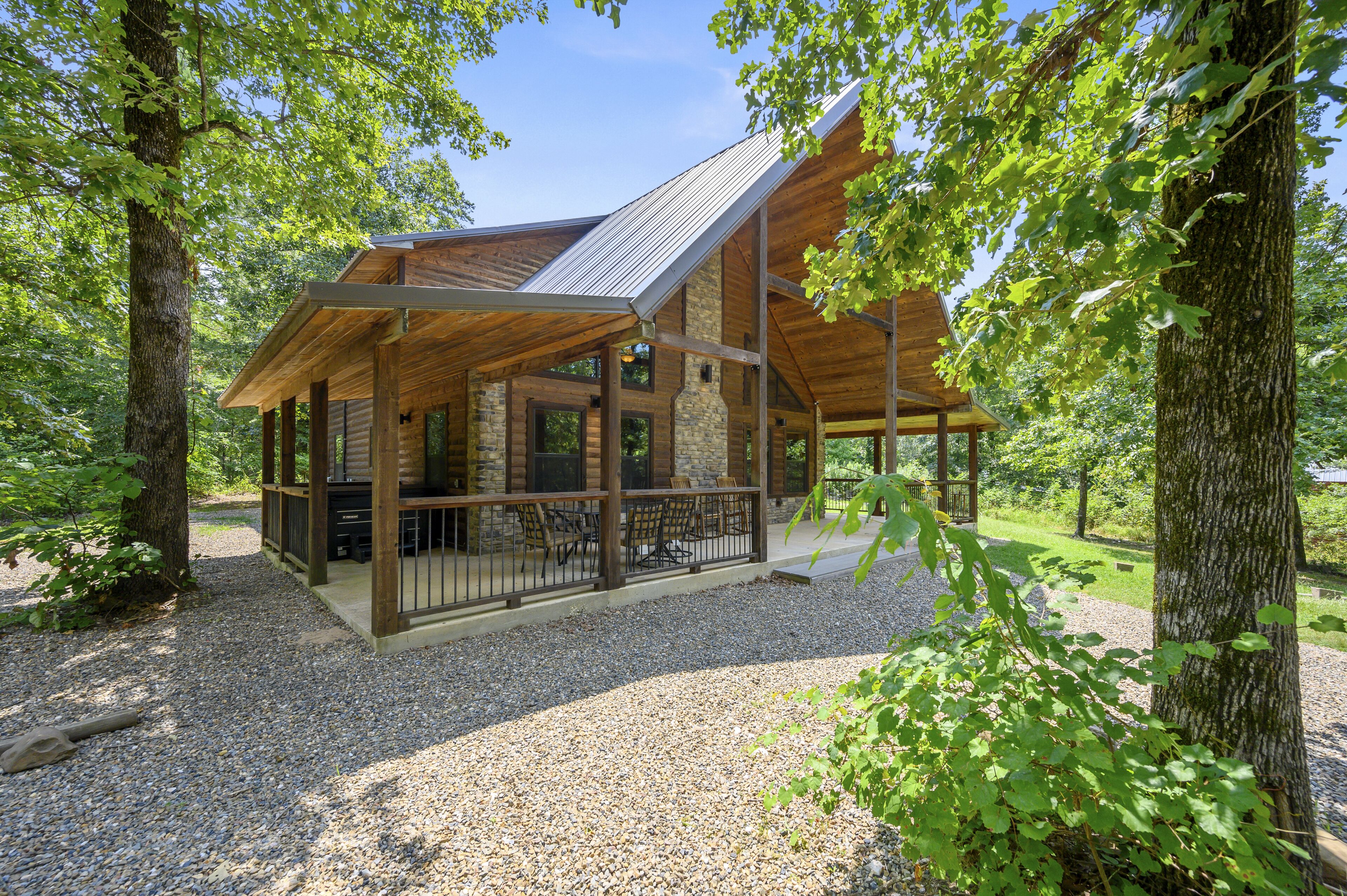 Een chalet met een houten gevel, stenen muren en een overdekte veranda met zitplaatsen.