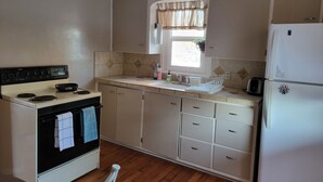 Cocina compacta con estufa, horno, pileta y refrigerador.