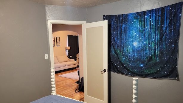 Un dormitorio con cama, un tapiz y una puerta que da a otra habitación.
