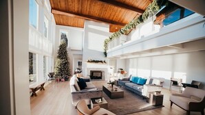 Un salon spacieux avec un haut plafond, de grandes fenêtres et une cheminée.