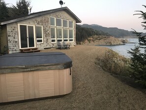 A house with a hot tub, a patio, and a view of the ocean.
