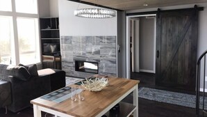 Una sala de estar moderna con una mesa de madera, chimenea y un ventanal grande.