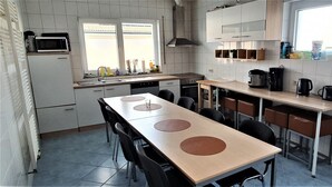 A modern kitchen with a dining area, equipped with a microwave, coffee maker, and a stove.