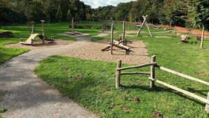 A playground with various play structures, a gravel path, and a fenced area.