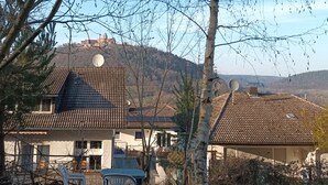 A house with a tiled roof, satellite dishes, and a view of a hill in the background.