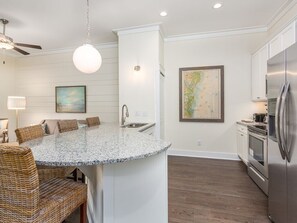 Enjoy meals in the kitchen with a central island and dining area, featuring a refrigerator, oven, and pendant light.