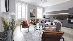 Ein modernes Wohnzimmer mit Sofa, Sesseln, einem Couchtisch und einem Essbereich.