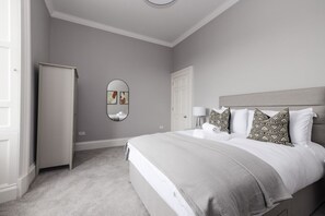 A bedroom with a bed, a wardrobe, a mirror, and a door. - Luxurious Apartment on Notable George Street (Edinburgh)
