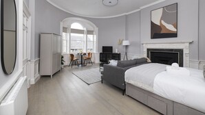 Camera da letto moderna con un letto, un camino, una TV e un'area pranzo con sedie e tavolo.