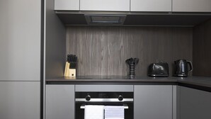 Una cucina moderna con mobili grigi, forno integrato e bollitore sul piano di lavoro.