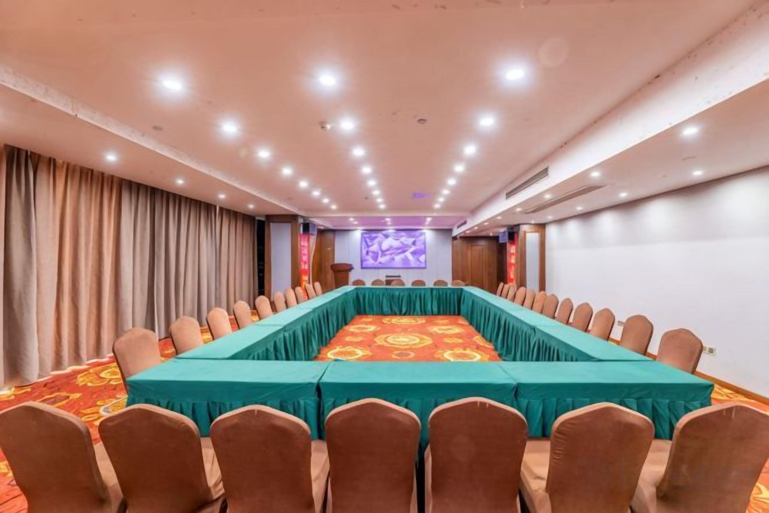 A conference room with a long table, chairs, and a projection screen.