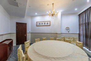 A conference room with a round table, chairs, a chandelier, and a door. - Zhongpu Hotel (Shangrao)