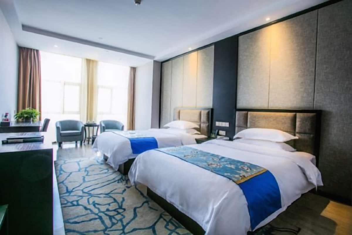 A hotel room with two beds, a desk, and a chair.