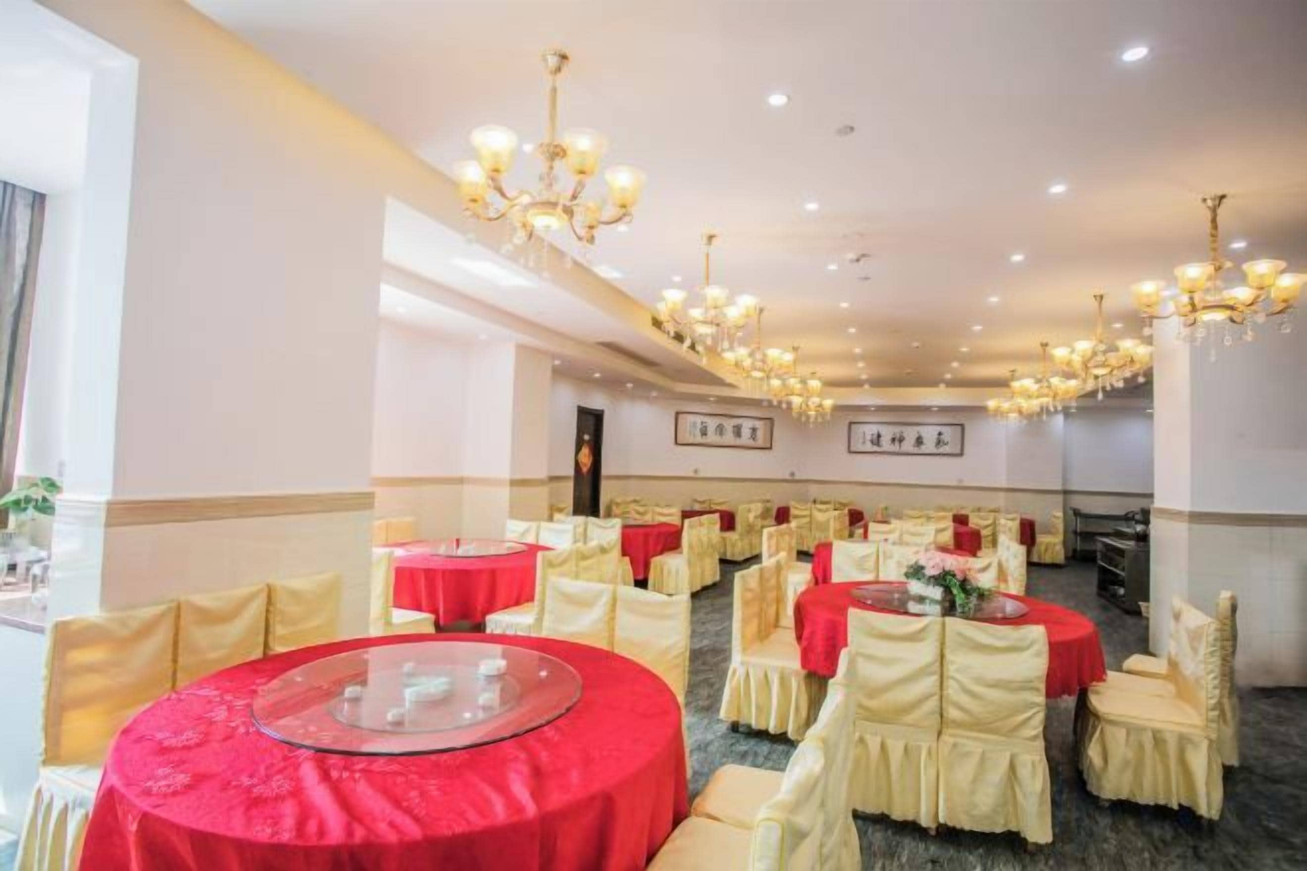 A banquet hall with round tables, chairs, and chandeliers.