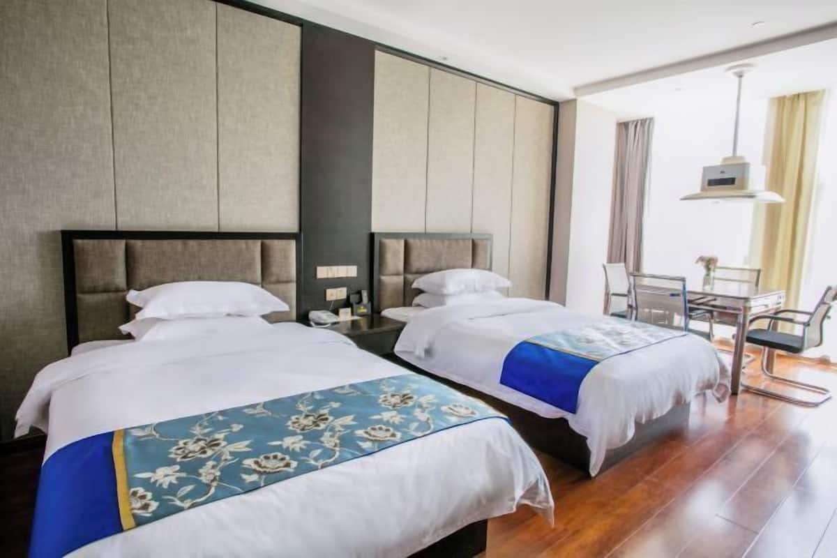 A hotel room with two beds, a desk, and a chair.
