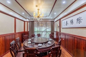 A conference room with a round table, chairs, a chandelier, wooden paneling, and a large window. - Zhongpu Hotel (Shangrao)