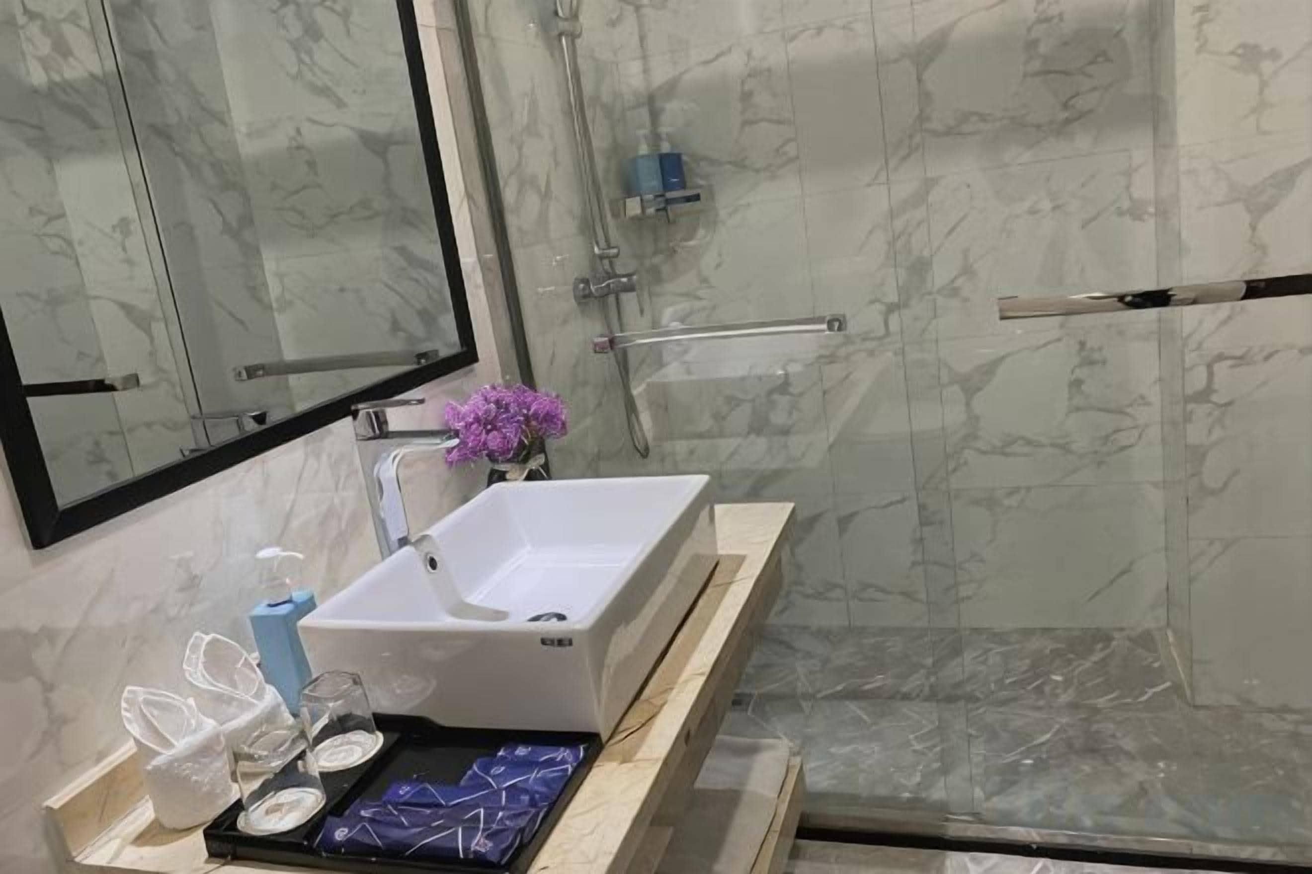 Un baño con un lavamanos blanco, un espejo y una zona de ducha.