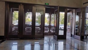 A lobby with a polished marble floor, a set of double doors with decorative glass panels, and a green exit sign above the doors. - Zhongpu Hotel (Shangrao)