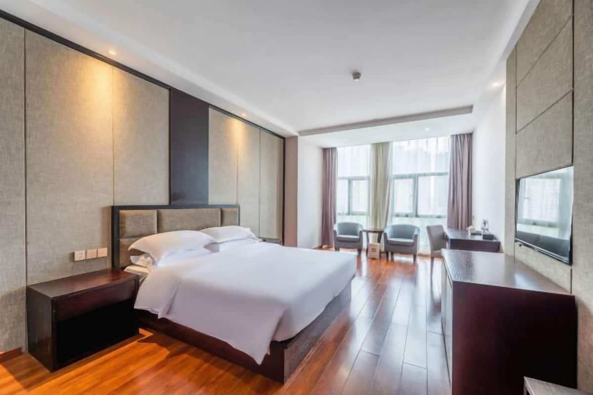 A modern hotel room with a large bed, a desk, and a TV.