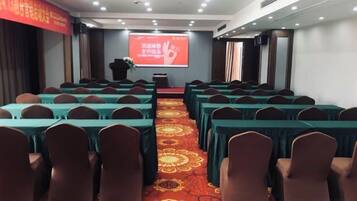 A conference room with rows of tables and chairs, a podium, and a projection screen.