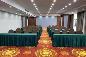 A conference room with rows of tables, chairs, and a carpeted floor. - Zhongpu Hotel (Shangrao)