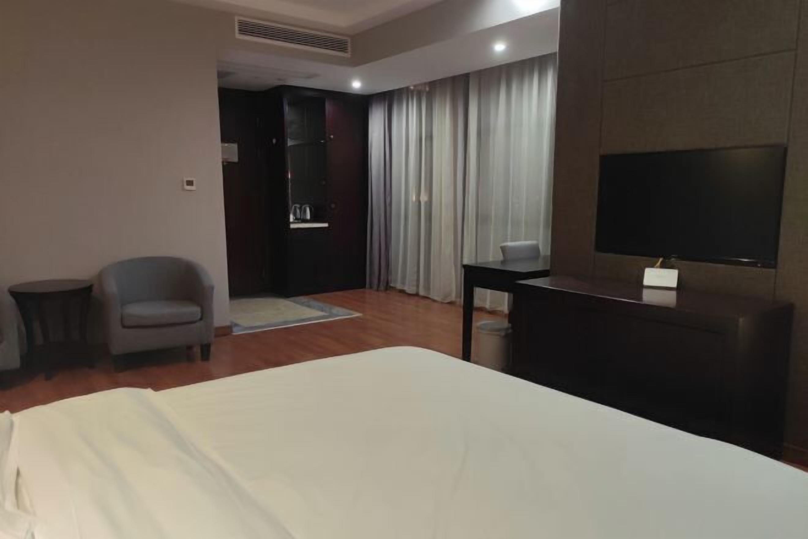 Una habitación de hotel con cama, televisión, escritorio, silla y una mesita.